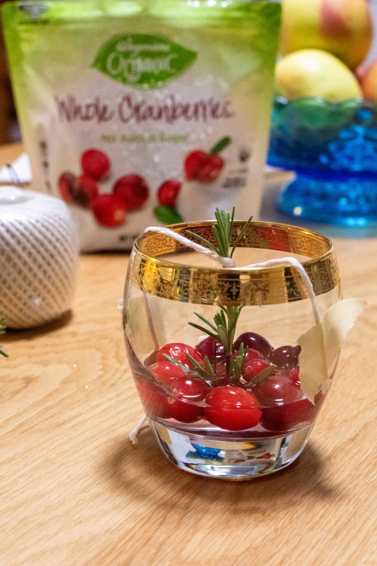 Rosemary held up by cotton twine in glass with cranberries