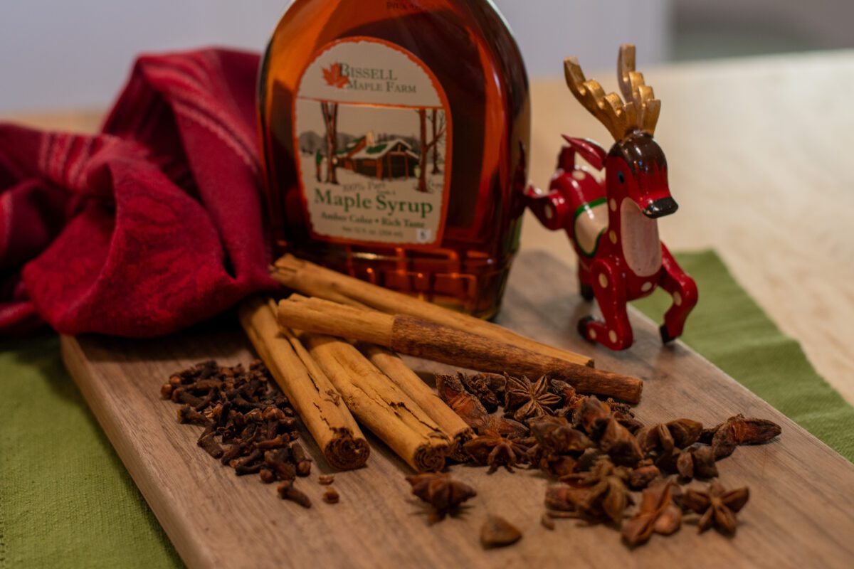 Maple syrup, cinnamon sticks, anise pods and cloves with a reindeer ornament