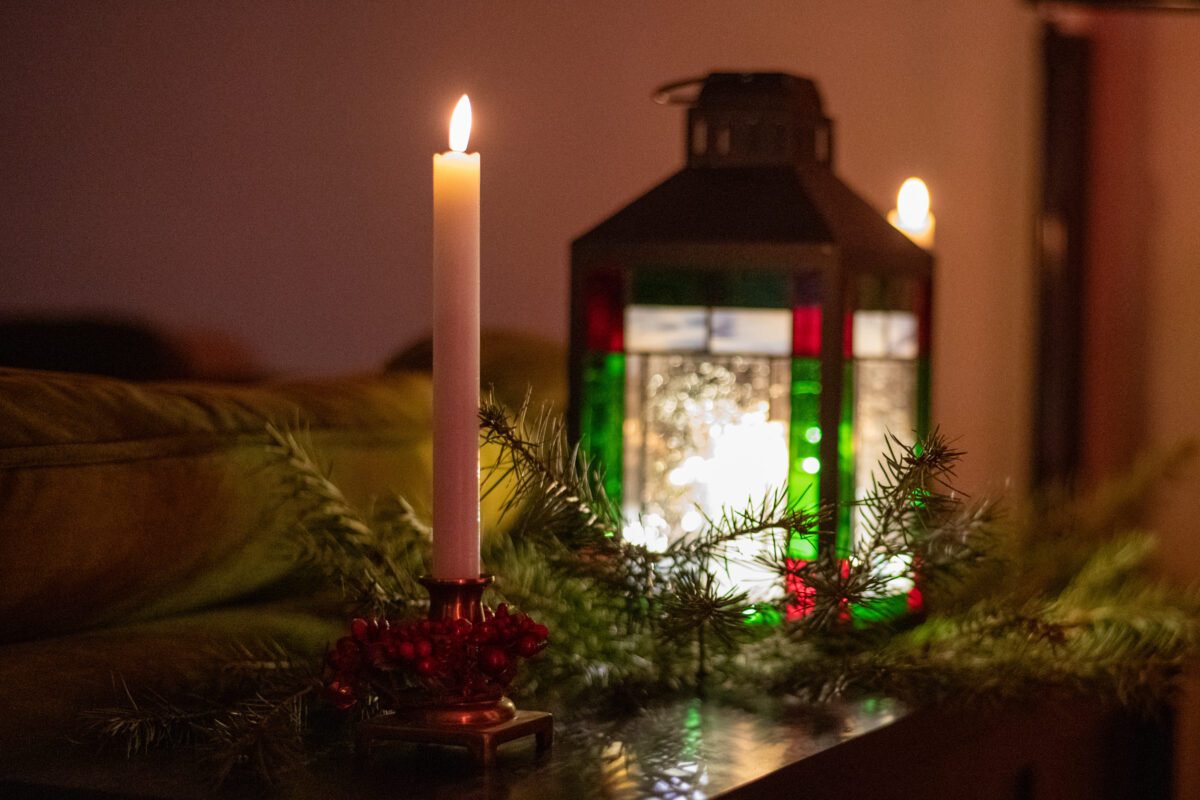 Candles among greens and a Christmas lantern.