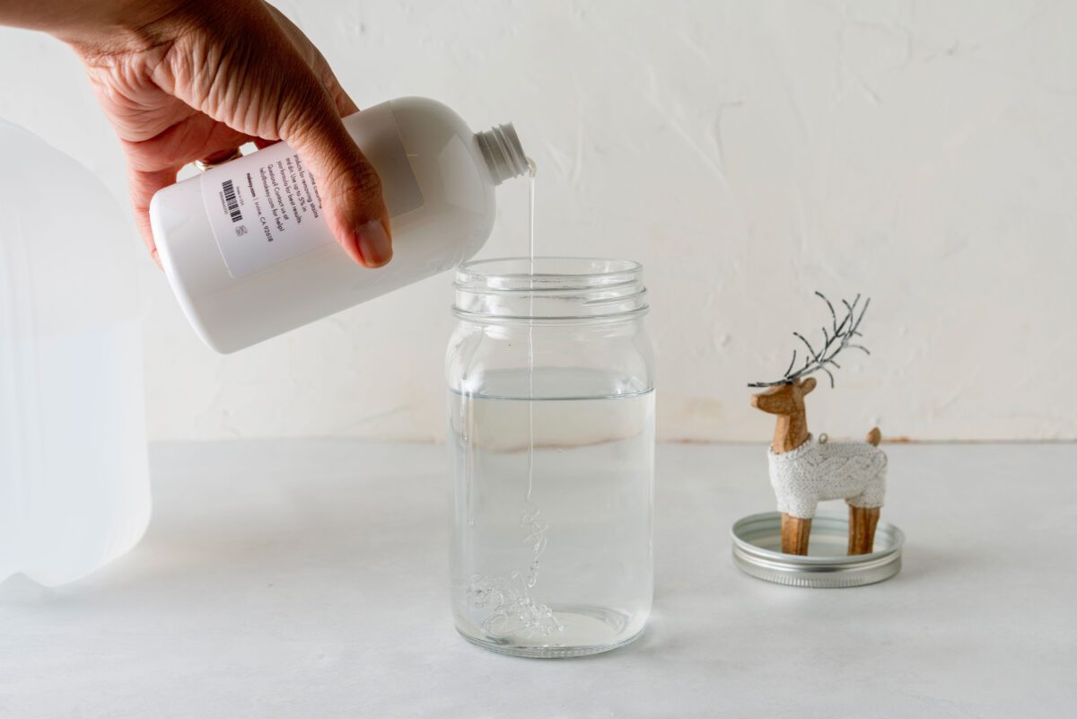 Adding glycerin to the jar during the process of making a DIY snow globe.