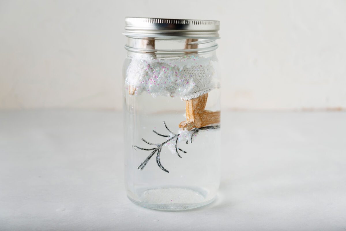 Upside-down reindeer inside a filled jar, completing the DIY snow globe.