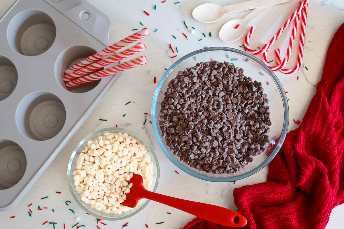 Ingredients used to make hot chocolate spoons, including chocolate chips, wooden spoons and a silicone mold. 