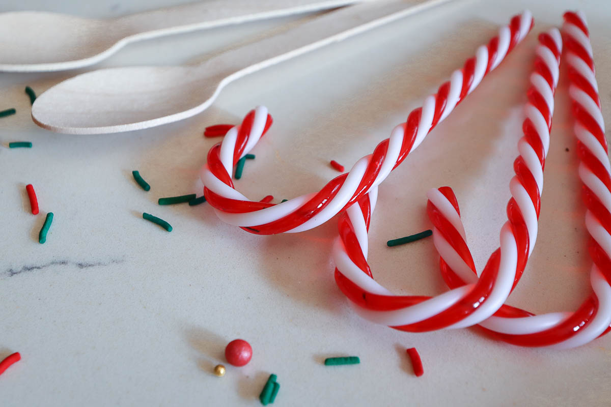 Plastic candy canes and wooden spoons used to make homemade hot chocolate sticks. 