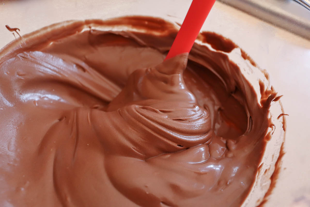 Melting chocolate in glass bowl with silicone spatula. 