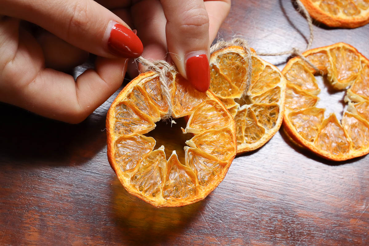 woman's hands making a dried orange garland