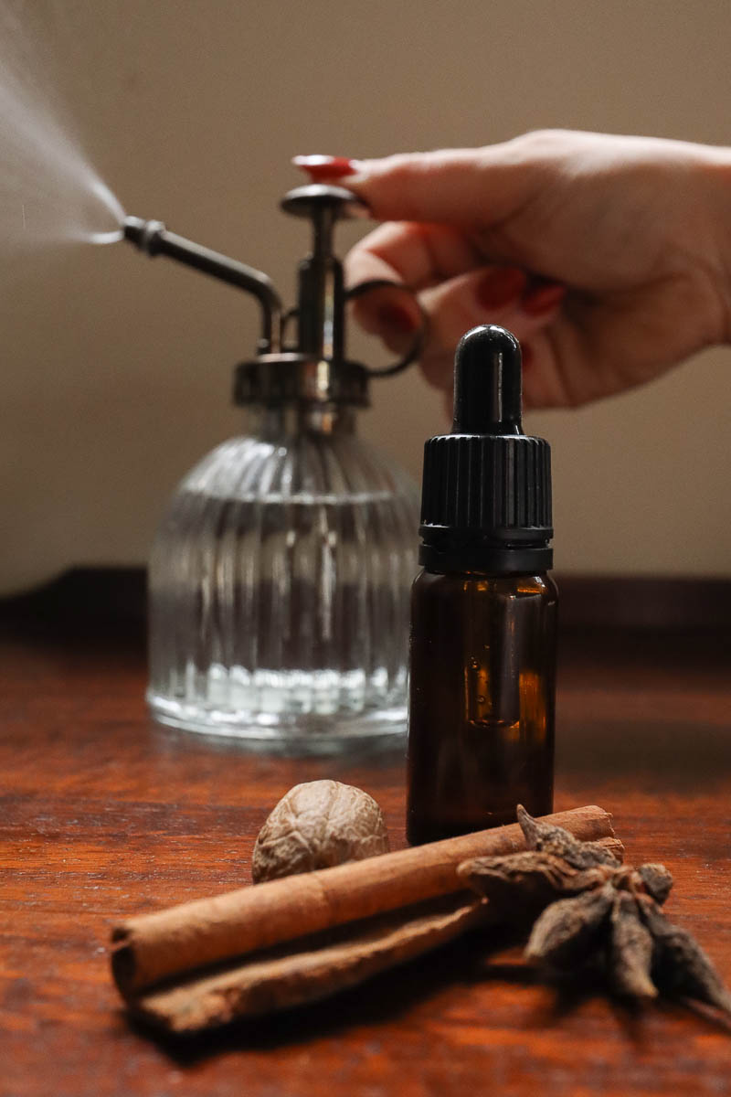 Essential oil bottle and woman's hand pressing mister in soft focus