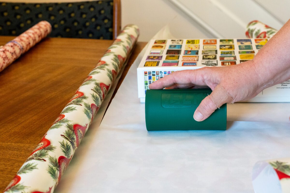 Woman's hand cutting wrapping paper with a Little Elf paper cutter. 