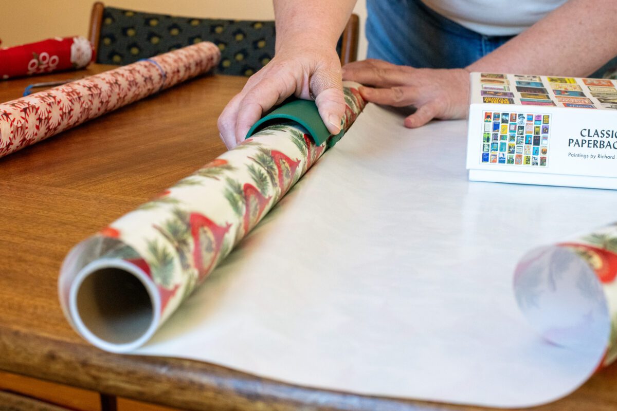 Woman using a Little Elf paper cutter to cut wrapping paper