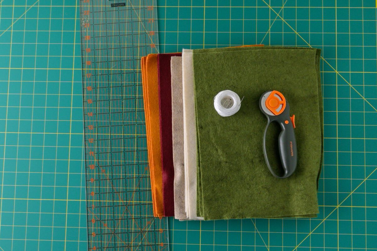 Stack of colorful felt sheets, Fiskars rotary cutter, and thread spool.