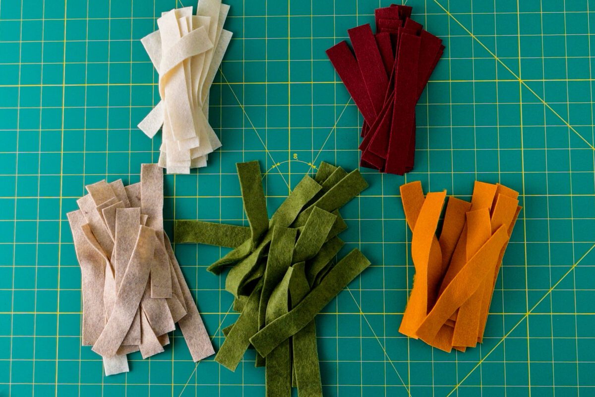 Assorted felt strips in green, orange, red, beige, and cream colors.