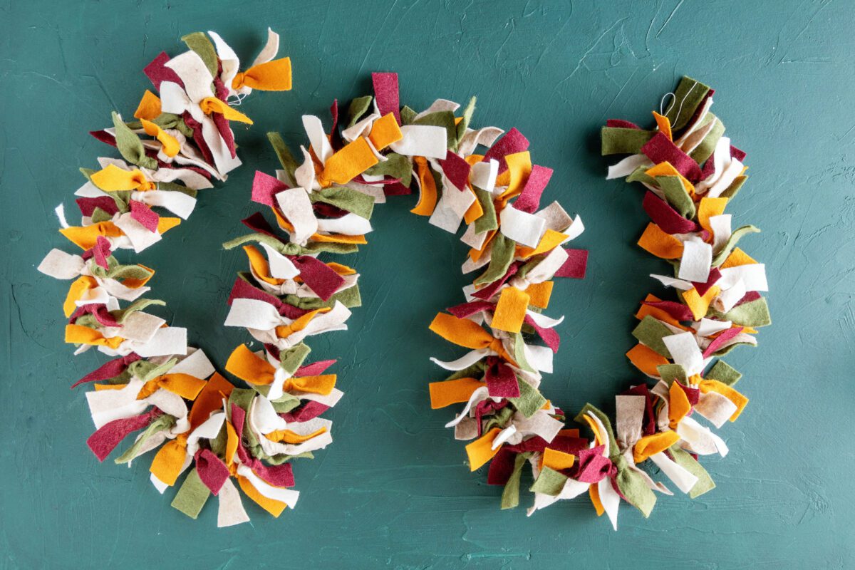 Completed colorful felt garland laid on a green textured background.