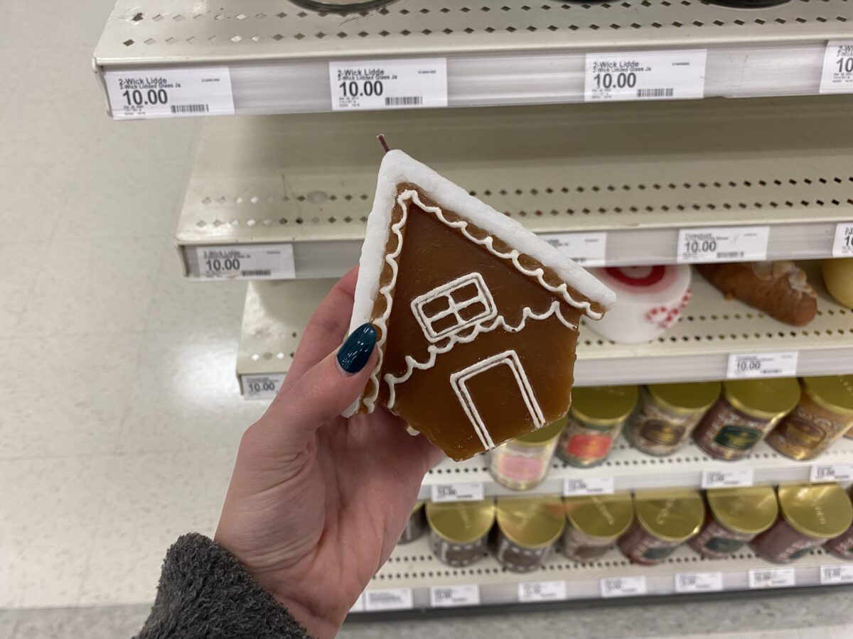 Woman's hand holding a gingerbread-shaped candle.