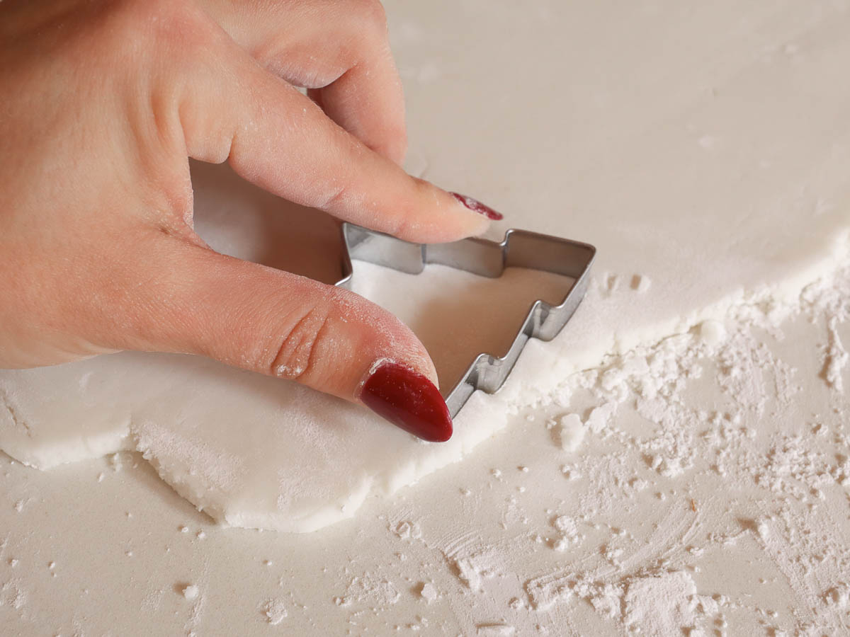 woman's hand pressing a cookie cutter into rolled out baking soda dough