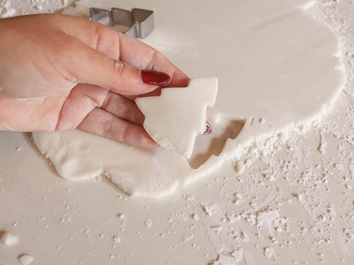 woman's hand holding Christmas tree cut out made with baking soda dough