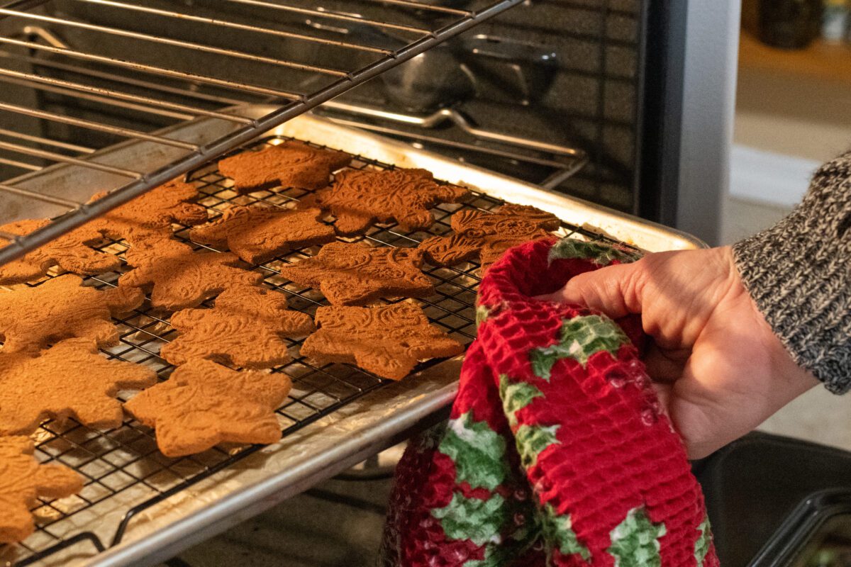 Woman using dish towel to take baking sheet out of oven