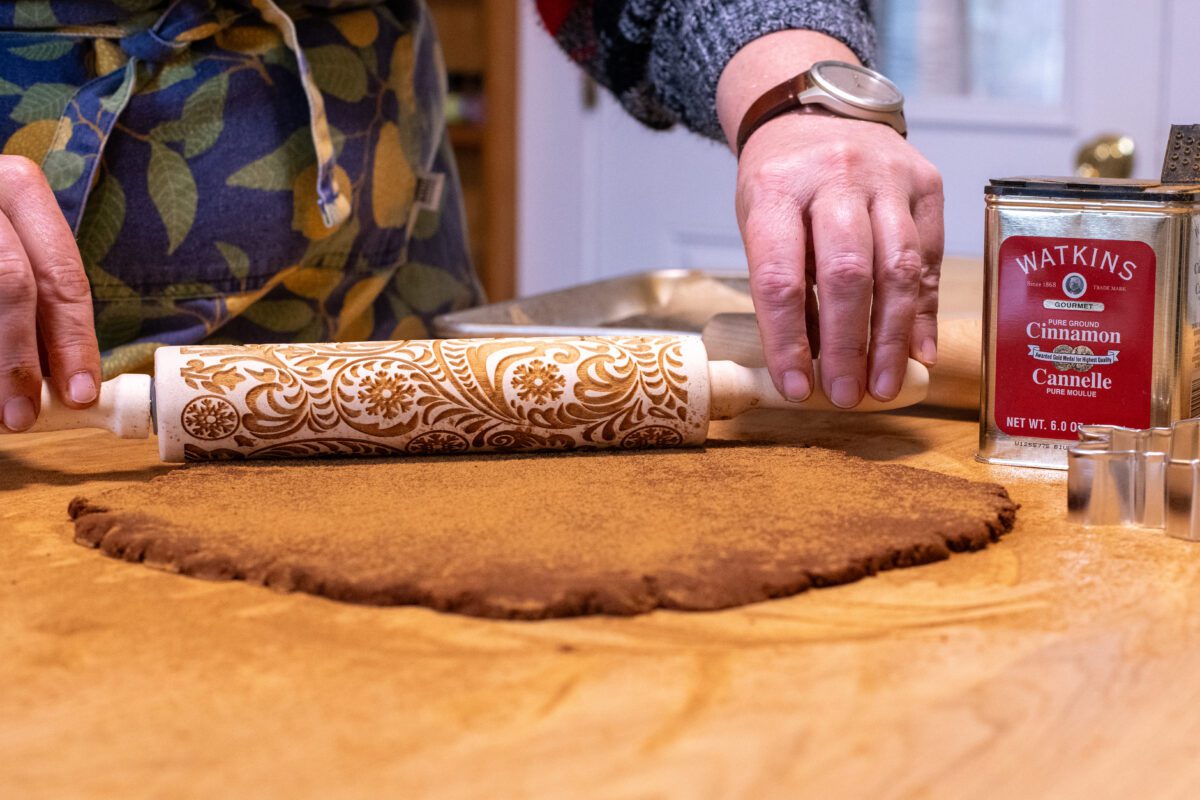 Woman's hands rolling out cinnamon ornament dough.