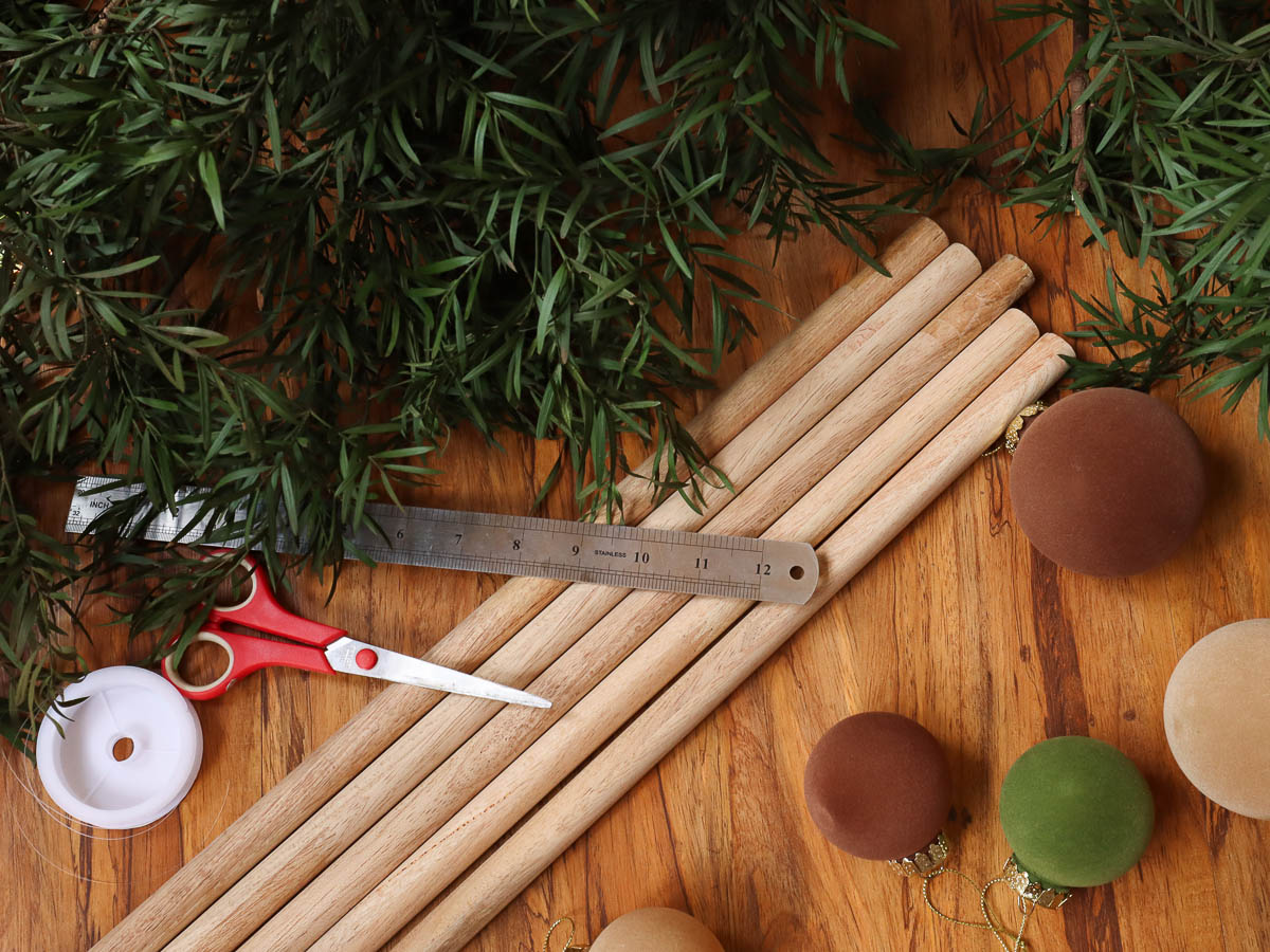 wood dowels, foliage, scissors, Christmas baubles and fishing line