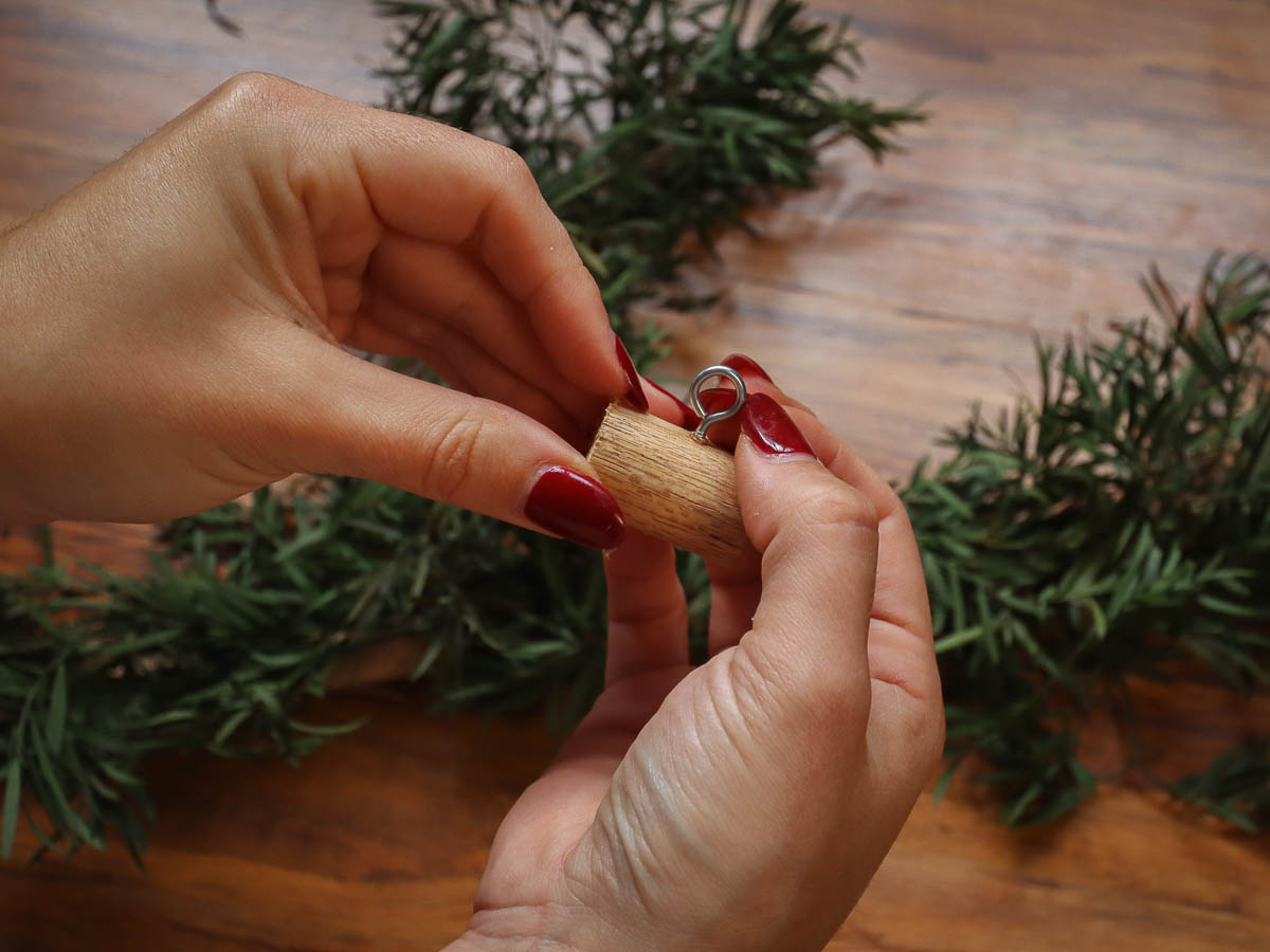 Woman's hands holding a piece of wooden dowel with an eye screw in it