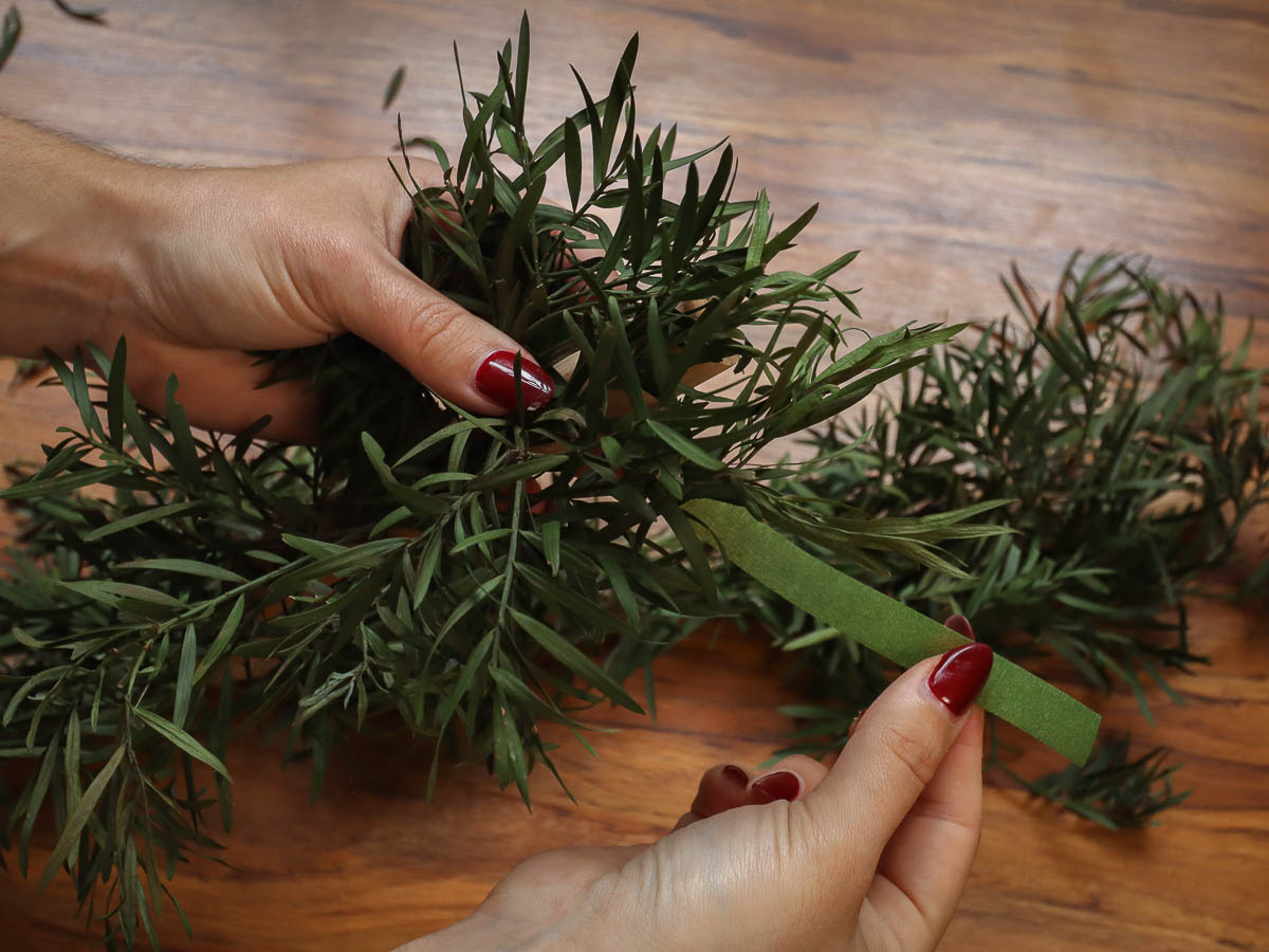 Woman's hands using floral tape to connect foliage