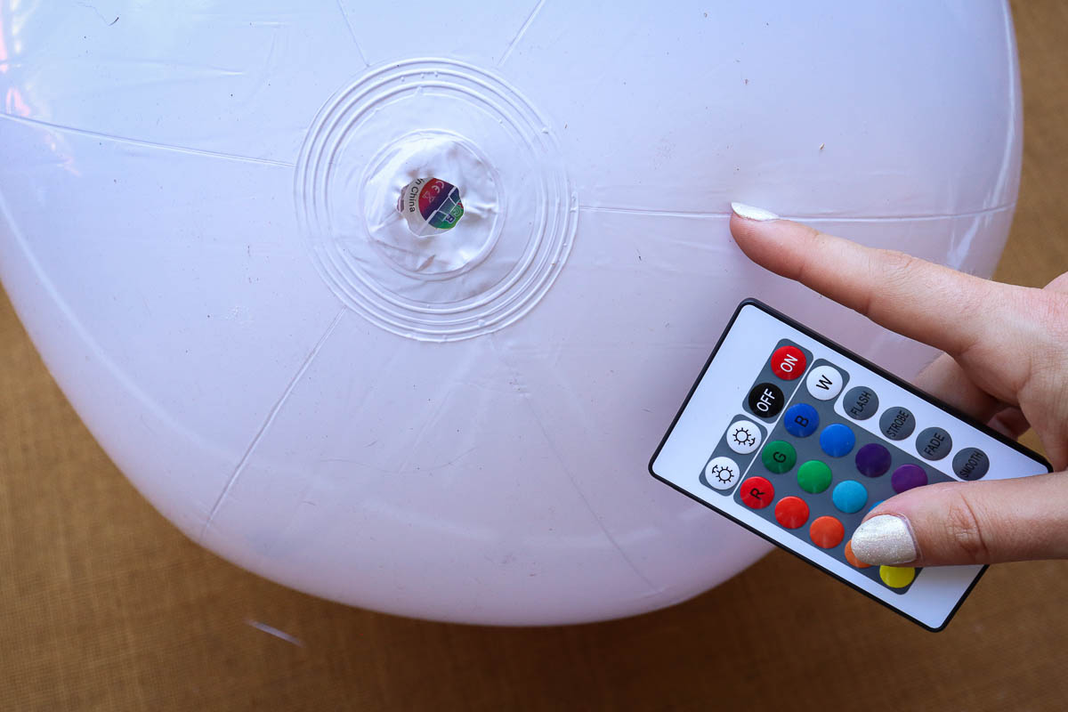 Woman's hand holding small remote and pointing to LED light in the bottom of a beach ball