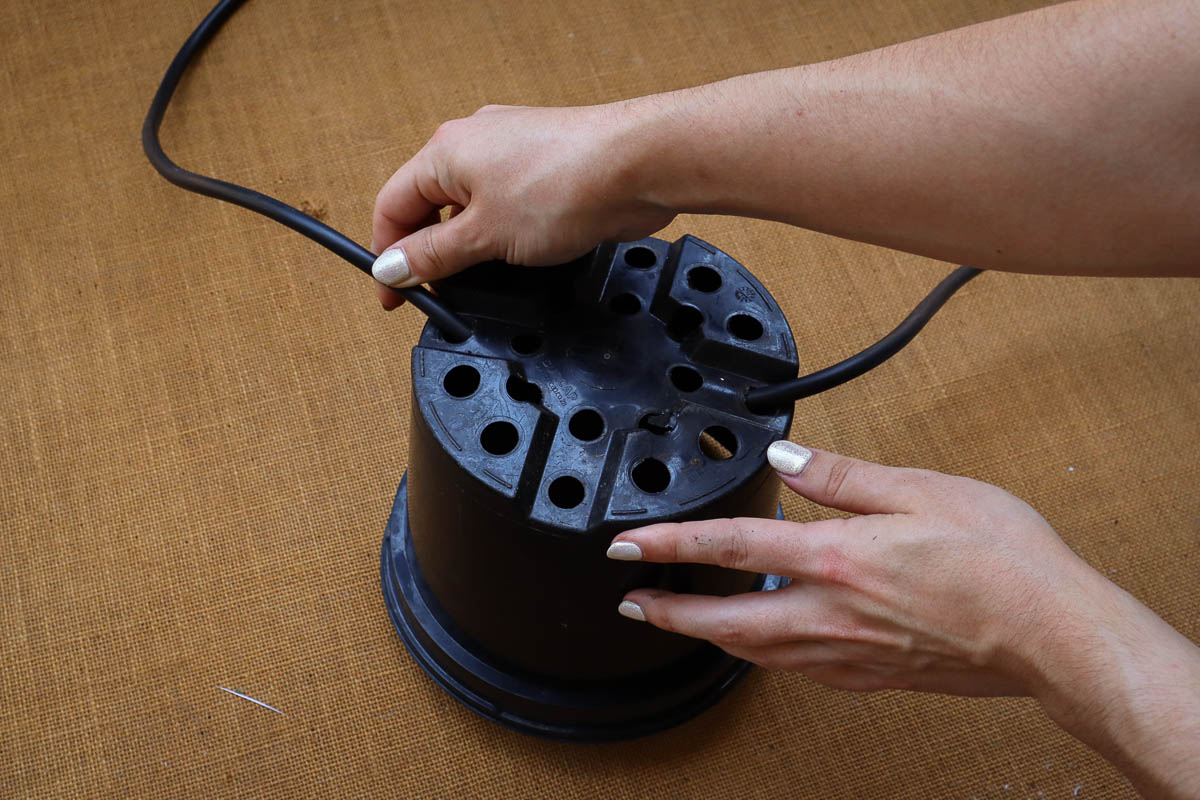 woman's hand stringing cord through bottom of a nursery pot