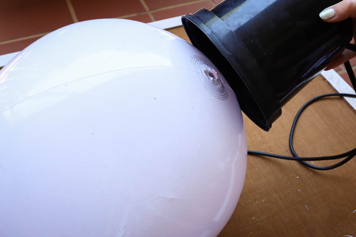 Woman's hand gluing a nursery pot to the top of a beach ball