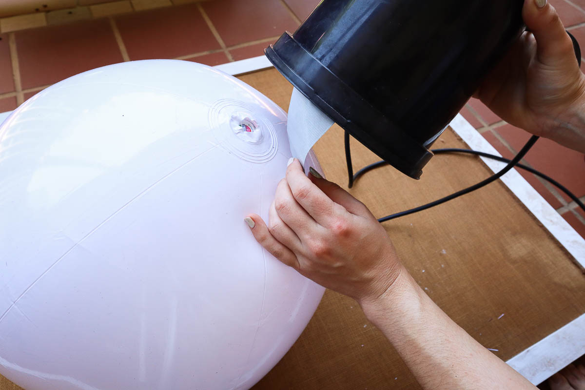 Woman's hand taping a nursery pot to the top of a beach ball